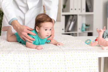 Pediatrician examining little baby in clinic