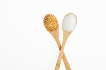 wooden spoons with white sugar and brown sugar on white background
