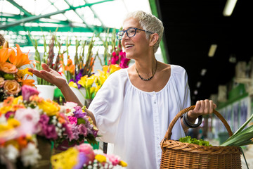 Charrming senior woman buying  flowers on  market