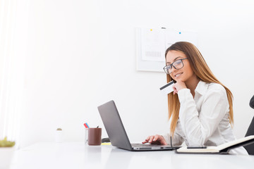 Attractive young businesswoman buying with a bank card on a notebook while sitting in her office.