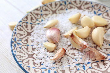Fototapeta na wymiar Plate with fresh garlic and salt on white wooden background, closeup