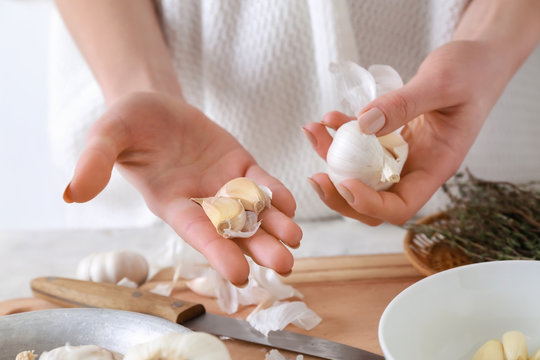 Woman with fresh garlic in kitchen