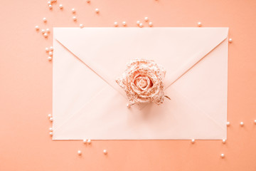 Paper envelope with beautiful flower and pearls on color background