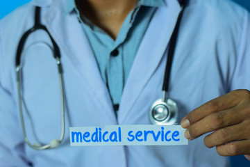 Doctor holding a card with text medical service. Medical and healthcare concept.