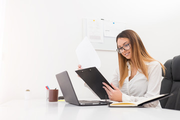 Happy cheerful young manager woman looking in charts in her office.