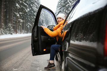Young woman sitting in car at winter resort
