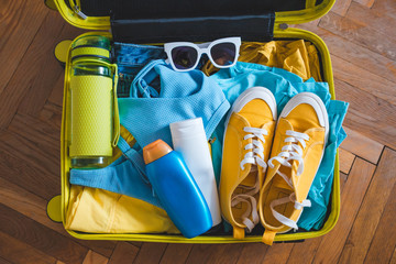 travel concept. yellow suitcase with different stuff around it