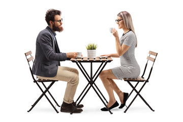 Young man and woman drinking coffee at a table - Powered by Adobe