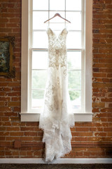 Gorgeous wedding dress hanging brick window