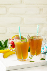 Fruit tea cups. Iced tea mango with mint on rustic white table. Copy space.