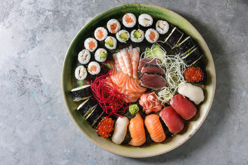 Sushi Set Nigiri Sashimi und Sushi-Rollen in keramischer Servierplatte mit Salat auf grauem Betonhintergrund. Flache Lage, Raum. Japanisches Menü