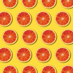 Red orange slices pattern on yellow color background. Minimal flat lay top view food texture 
