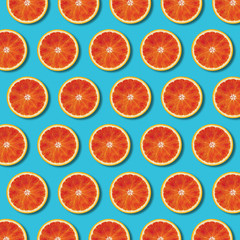 Red orange slices pattern on vibrant turquoise color background. Minimal flat lay top view food texture 
