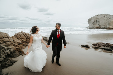 The bride and groom are walking along the beach. Panoramic view.