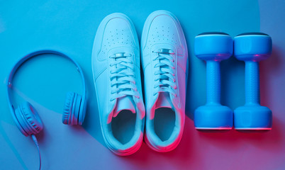 Lifestyle concept. Dumbbells, headphones, sneakers. Retro wave, neon light, ultraviolet. Top view, minimalism