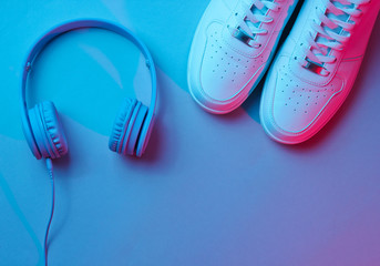 Sneakers with wireless headphones. Retro wave, neon light, ultraviolet. Top view, minimalism