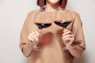 Redhaired girl sommelier on white background and hold with two glasses of red wine. Concept alcoholism, alcohol addiction, bad habit, collection rare wine, blind degustation