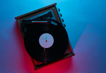 Vinyl player with lp record. Retro wave, red blue neon light, ultraviolet. Top view, minimalism