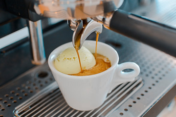 Affogato coffee with ice cream on a ceramic cup with coffee pouring from espresso machine