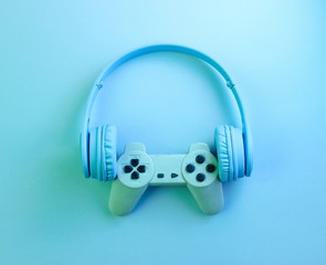 Gаmer concept. Gamepad with headphones. 80s. Retro wave, blue neon light, ultraviolet. Top view, minimalism © splitov27