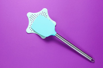 Silicone spatula for cooking with a metal handle on a stand on a purple background. Minimalism