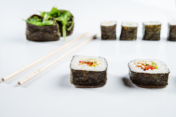 Two chopsticks, sushi and rolls on white background