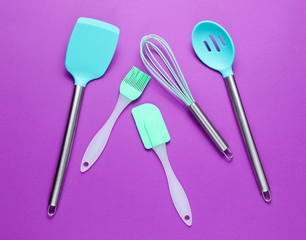 Silicone tools with metal handles for cooking on purple background