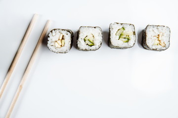 Two chopsticks, sushi and rolls on white background