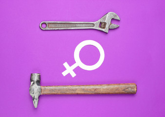 Women choose male work. Feminism. Gender equality. Hammer, wrench, symbol of feminist on purple background. Top view
