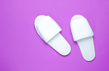 White hotel slippers on a purple background. Top view. Minimalism