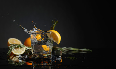 Cocktail gin-tonic with lemon slices and twigs of rosemary.