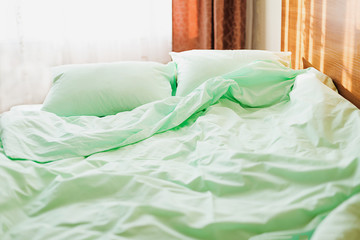Fototapeta na wymiar Minty green bedding on the bed at the early morning