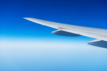 Fototapeta na wymiar Plane wings flight with the blue sky background