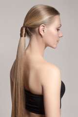 woman with a hair tail. Clean skin of the face. Blonde. Gray background