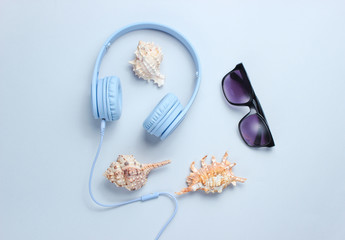 Headphones, sunglasses, shells on gray background. Beach music. Top view.