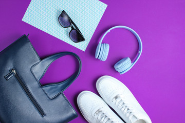 Modern accessories on a creative color background. White sneakers, leather bag, headphones, sunglasses. Objects. Top view, flat lay