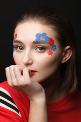 Photo of a young girl with makeup in the form of flowers in red and blue