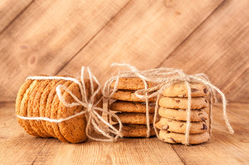 Various shortbread, oat cookies, chocolate chip biscuit on dark rustic wooden table.