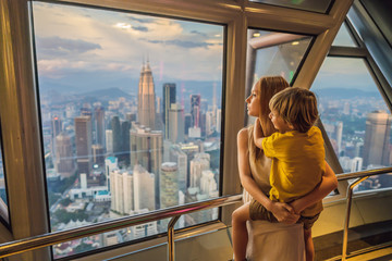 Mom and son are looking at Kuala lumpur cityscape. Panoramic view of Kuala Lumpur city skyline...