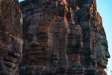 Stone faces in Bayon, Angkor Thom temple, selective focus sunset light. Buddhism meditation concept, world famous travel destination, Cambodia tourism.