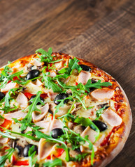 Pizza with Mozzarella cheese, mushrooms, ham, tomato sauce, pepper, olives, Spices and Fresh arugula. Italian pizza on wooden table background