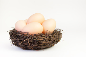 Beige eggs in the nest of branches on a white background