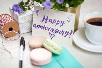 Writing a Happy Anniversary postcard on white marble table