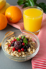 Healthy breakfast in a bowl with oatmeals, frozen berries, fresh strawberries, mint. Oat porridge with fruits.