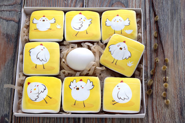 Gingerbreads with images of chickens are in a box. Egg is in the center of a box. Gingerbreads are a dessert for Easter. Egg is Easter symbol.
