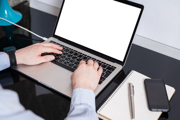 Freelancer at his working place. Empty laptop screen mockup. .A man is working by using a laptop mockup computer on vintage wooden table. Hands typing on a keyboard. Top view.