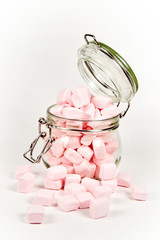 Pink marshmallows in the glass jar, isolated on white background