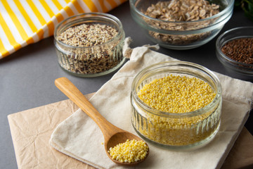 Raw millet groats in glass bowl with variouse cereals on the background. Healthy food, cereals....