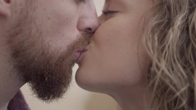 Close up kissing bearded man and pretty woman. Beautiful couple show their tenderness to each other. Lovers happy together