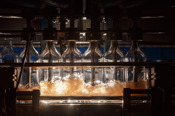 Automatic filling machine pours Liquid into glass bottles. Brewing production. Industrial background.